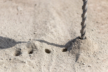 People are using electric drill,He drilled concrete to put steel anchor.