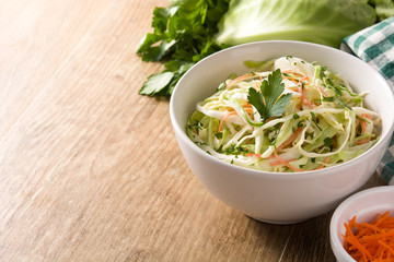 Coleslaw salad in white bowl on wooden table