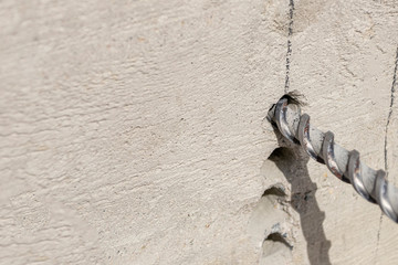People are using electric drill,He drilled concrete to put steel anchor.