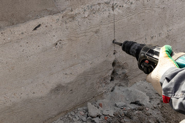 People are using electric drill,He drilled concrete to put steel anchor.