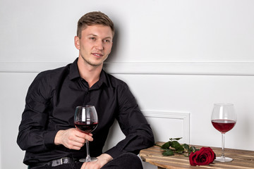 Young handsome man sitting by table in cafe while waiting for his girlfriend