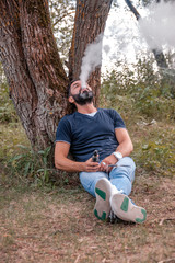 Modern vaper enjoying an electronic cigarette in nature. Electronic cigarette concept.
