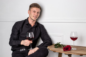 Young handsome man sitting by table in cafe while waiting for his girlfriend