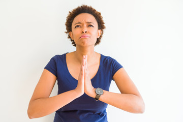 Young beautiful african american woman over white background begging and praying with hands together with hope expression on face very emotional and worried. Asking for forgiveness. Religion concept.