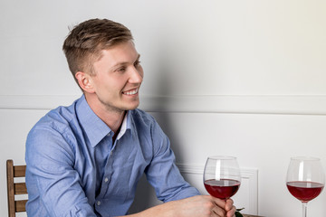 Young handsome man sitting by table in cafe while waiting for his girlfriend