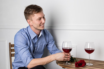 Young handsome man sitting by table in cafe while waiting for his girlfriend