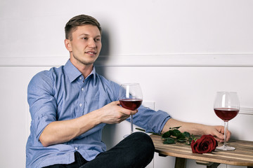 Young handsome man sitting by table in cafe while waiting for his girlfriend