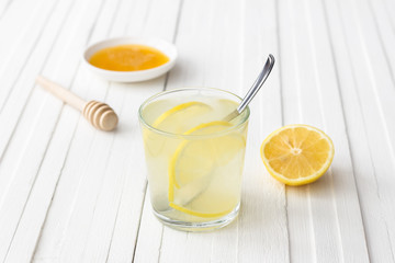 Lemon water with honey in a glass on a white background