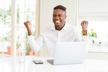 African american business man working using laptop celebrating surprised and amazed for success with arms raised and open eyes. Winner concept.