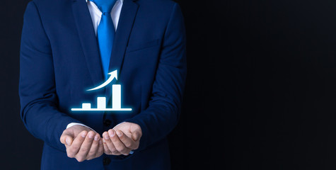 businessman on black background; in hand an illustrative growth chart; business concept
