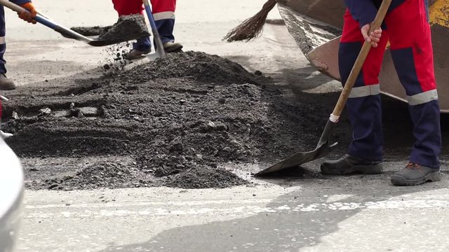 Workers remove shovels old cut asphalt from the road for laying new asphalt. Preparation of the road for laying new asphalt.