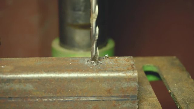 Macro shot of a drill that pierces a sheet of iron or steel. The tip of the metal drill with a circular motion pierces the material. Concept:engineering,industry,technology, locksmith and construction