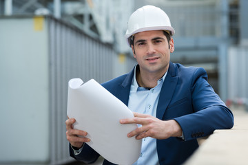 construction engineer posing while holding a blueprint