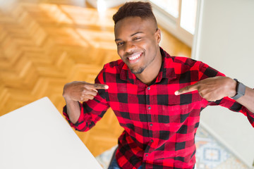 Overhead angle of handsome african american man looking confident with smile on face, pointing...