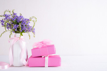 Happy mothers day concept. Gift box with purple flower on white wooden table background.