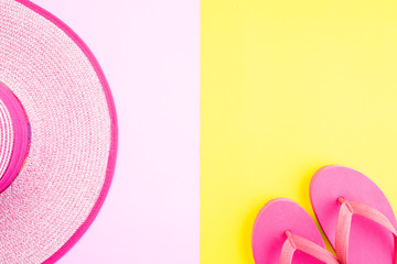 Beach accessories sunglasses, flip flop starfish beach hat and sea shell on pink and yellow background for summer holiday and vacation concept.