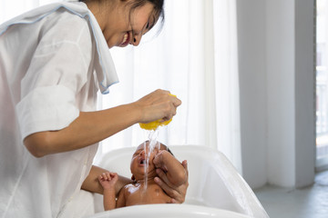 Obraz na płótnie Canvas Asian mother bathing her infant baby