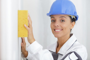 woman builder cleaning wall