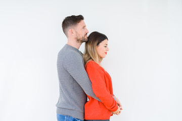 Young beautiful couple togheter over isolated background looking to side, relax profile pose with natural face with confident smile.