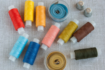 colored threads for sewing, centimeter ribbons and thimbles on a light gray background close-up, copy space