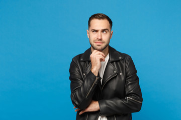 Stylish young bearded man in black leather jacket white t-shirt put hand prop up on chin isolated on blue wall background studio portrait. People sincere emotions lifestyle concept. Mock up copy space