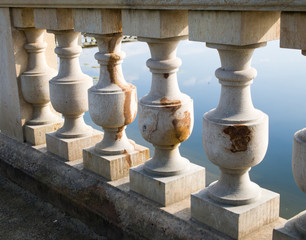 Balustrade in the park lit by afternoon sunlight. Stone railing near water.