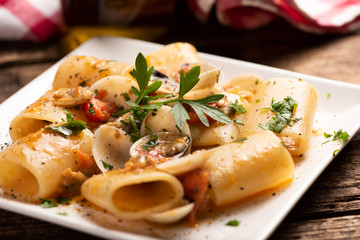Paccheri pasta with clams on white plate