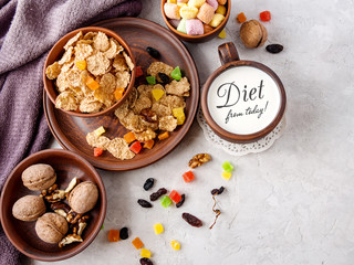 Morning still life. Healthy breakfast (wheat flakes, walnuts, candied fruits, raisins, milk) on a gray textured background.top view