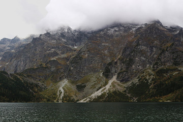 Clouds above the peaks of the mountains and a mountain lake.