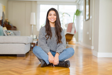 Young beautiful woman sitting on the floor at home with a happy and cool smile on face. Lucky person.