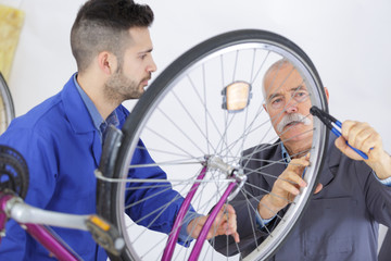 bicycle mechanic and apprentice repairing a bike in workshop
