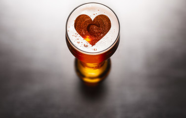 Loving beer concept. Heart symbol on beer glass foam on black table, view from above - 270383391