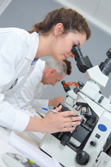 female scientist looking through a microscope in laboratory