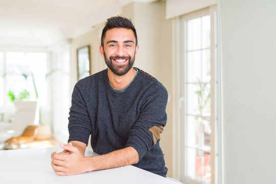Handsome hispanic man wearing casual sweater at home with a happy and cool smile on face. Lucky person.
