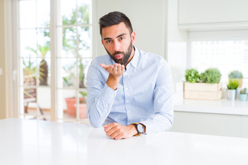 Handsome hispanic business man looking at the camera blowing a kiss with hand on air being lovely and sexy. Love expression.