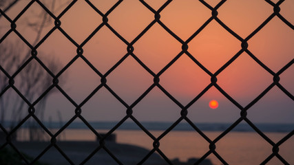 Naklejka premium Sunset captured through the fence