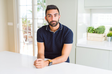 Handsome hispanic man at home with serious expression on face. Simple and natural looking at the camera.