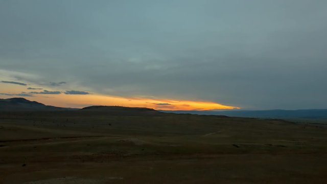Time-lapse of the moving clouds during sunset over a vast landscape field