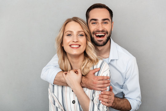 Photo closeup of cute couple in casual clothing smiling at camera and hugging each other