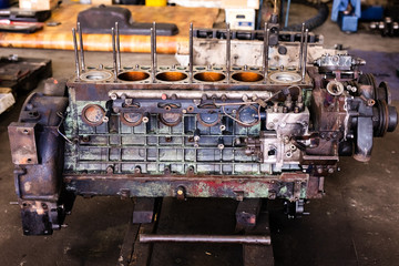 Mechanic repairs old motor of truck in a car repair station. Disassemble engine block vehicle. Motor capital repair. Car service concept