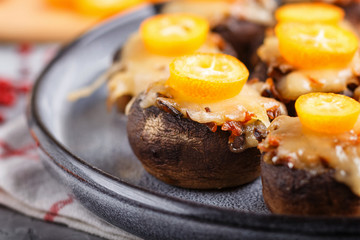 stuffed fried champignons with cheese, kumquats and green peas on a gray concrete background. side view, close up, macro.