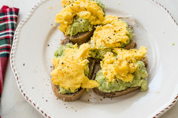Scrambled Eggs with Avocado on Toast Bread for Breakfast.