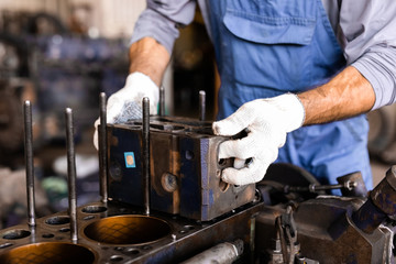 Mechanic repairs old motor of truck in a car repair station. Disassemble engine block vehicle. Motor capital repair. Car service concept