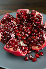 Organic pomegranate on a grey ceramic plate. Dark wooden table, high resolution