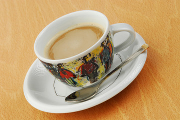 A cup of coffee in a colored cup on wooden background