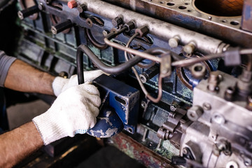 Mechanic repairs old motor of truck in a car repair station. Disassemble engine block vehicle. Motor capital repair. Car service concept