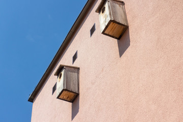 Two bird boxes hanging high on the wall of building - 270388317