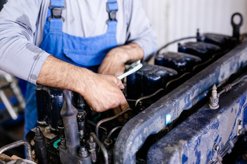 Mechanic repairs old motor of truck in a car repair station. Disassemble engine block vehicle. Motor capital repair. Car service concept