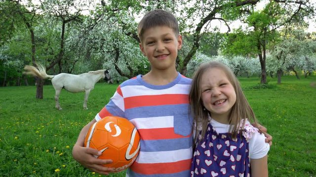 Happy embraced brother and sister in blooming spring garden. Static shot