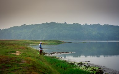Man fishing with fishing-hook in morning captured from Ithikkunnu, Padapuzha